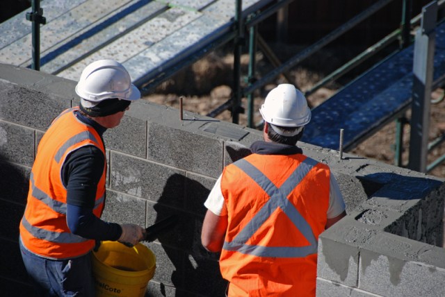 Jib (left) cleans off the excess concrete off the honed blocks, which will be visible after the house is built. Nathan looks at the long reo sticking out of the tops of the blocks and the cast-in plate which the steel beam will be welded to.
